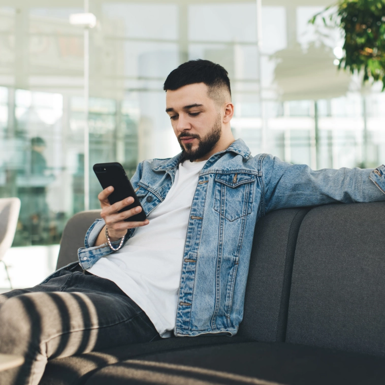 homem olhando o celular sentado no sofá